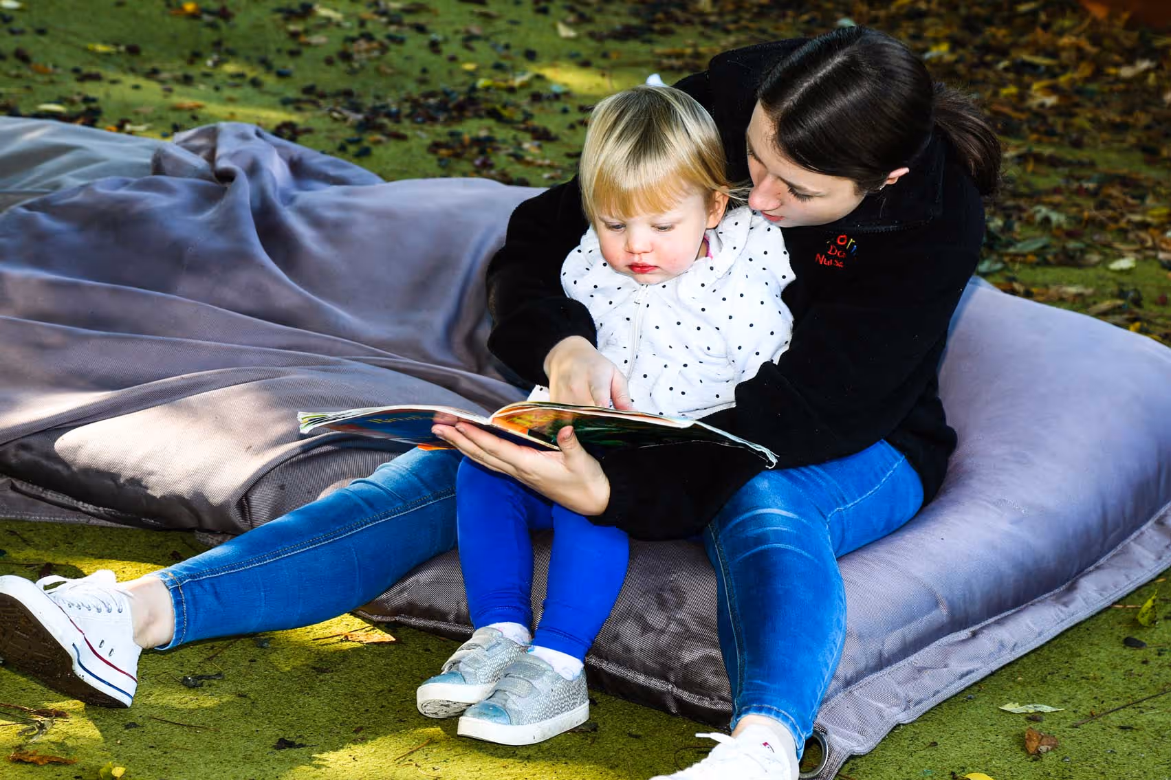 Young child cuddling a teacher reading