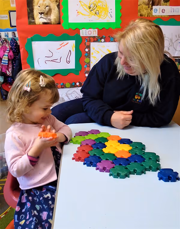 Teach and young girl playing with building blocks