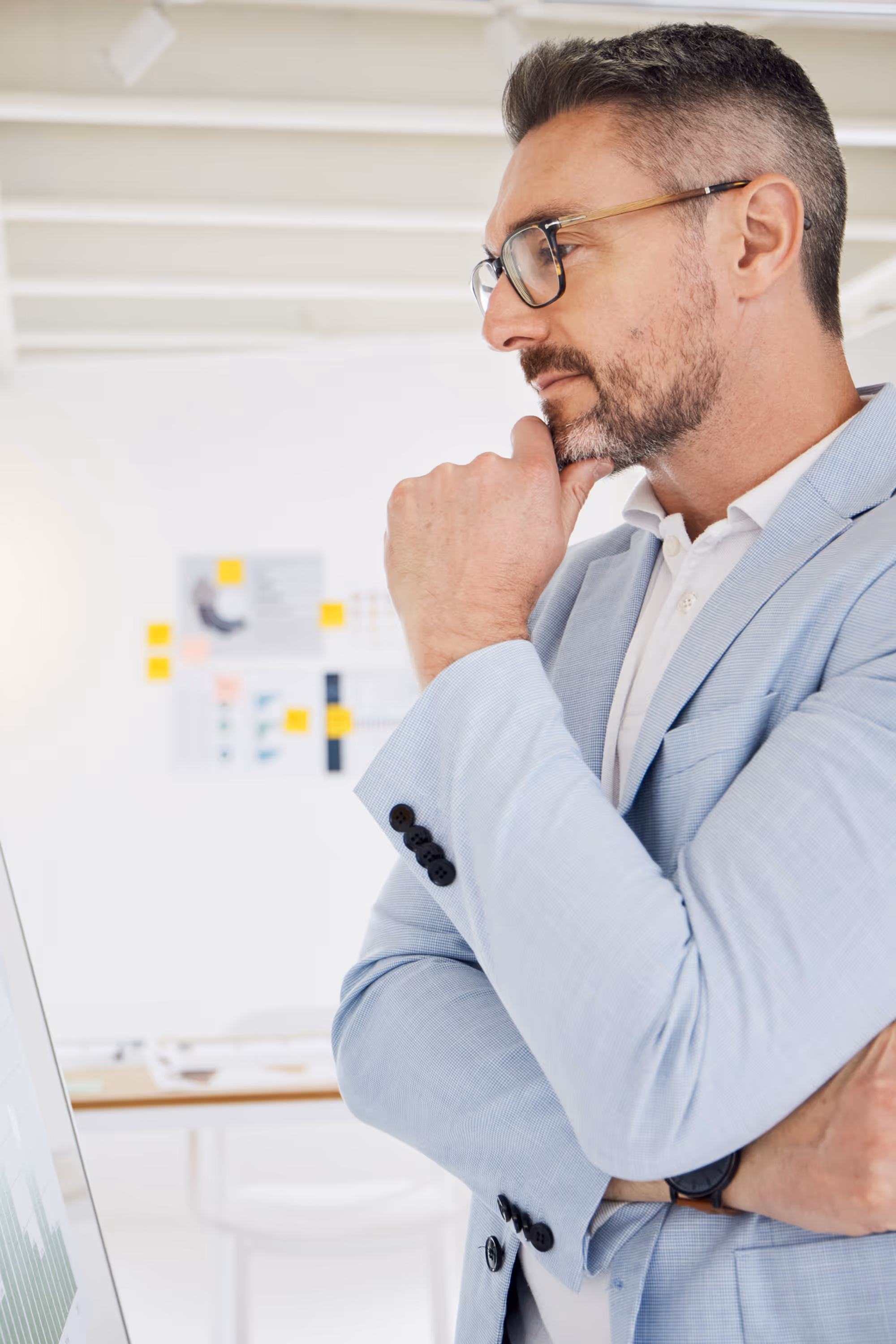 Business professional reviewing data on a screen, thinking through decisions while analyzing information in an office setting.