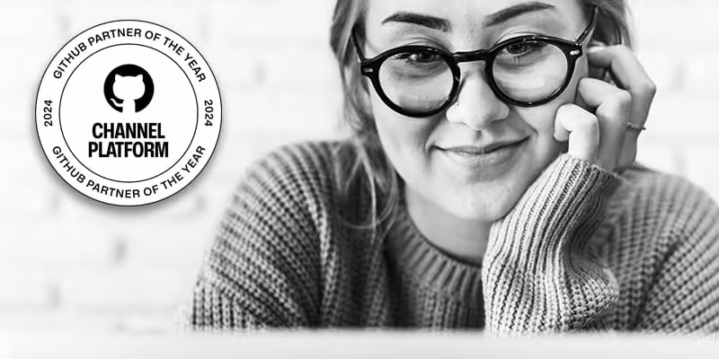 Smiling person wearing glasses and a sweater looking at a screen with GitHub Partner of the Year 2024 badge.
