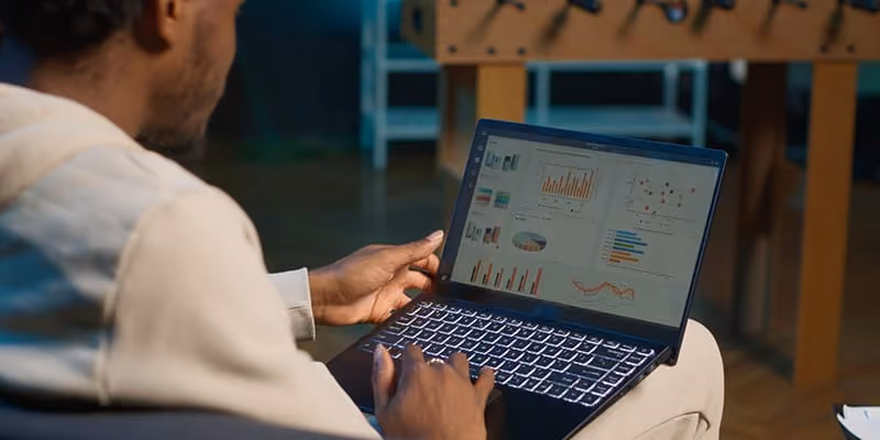 A man working on a laptop looking at charts and graphs.