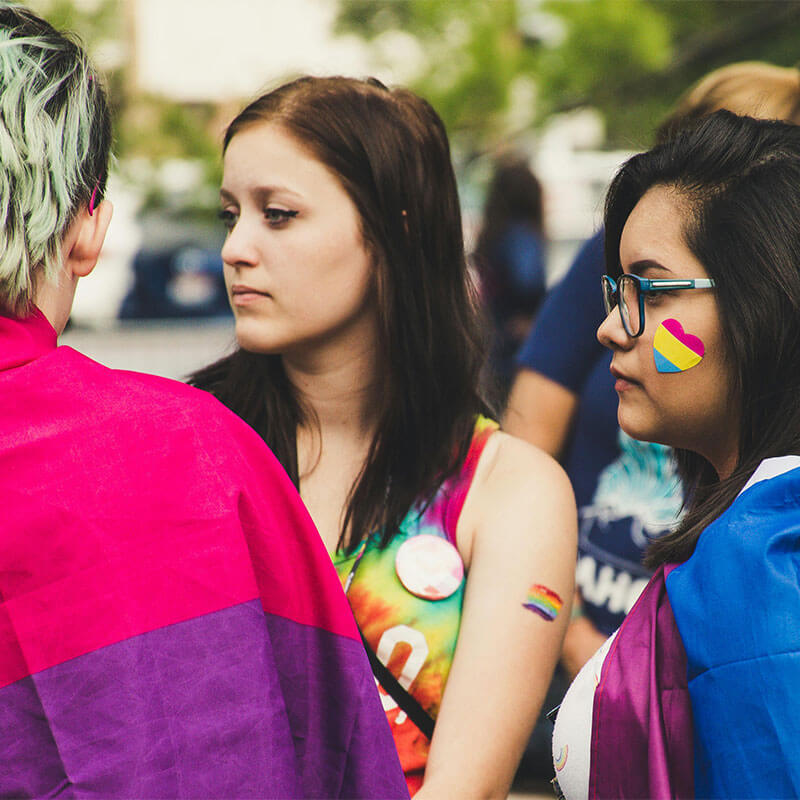 A diverse group of people conversing while standing close to one another.
