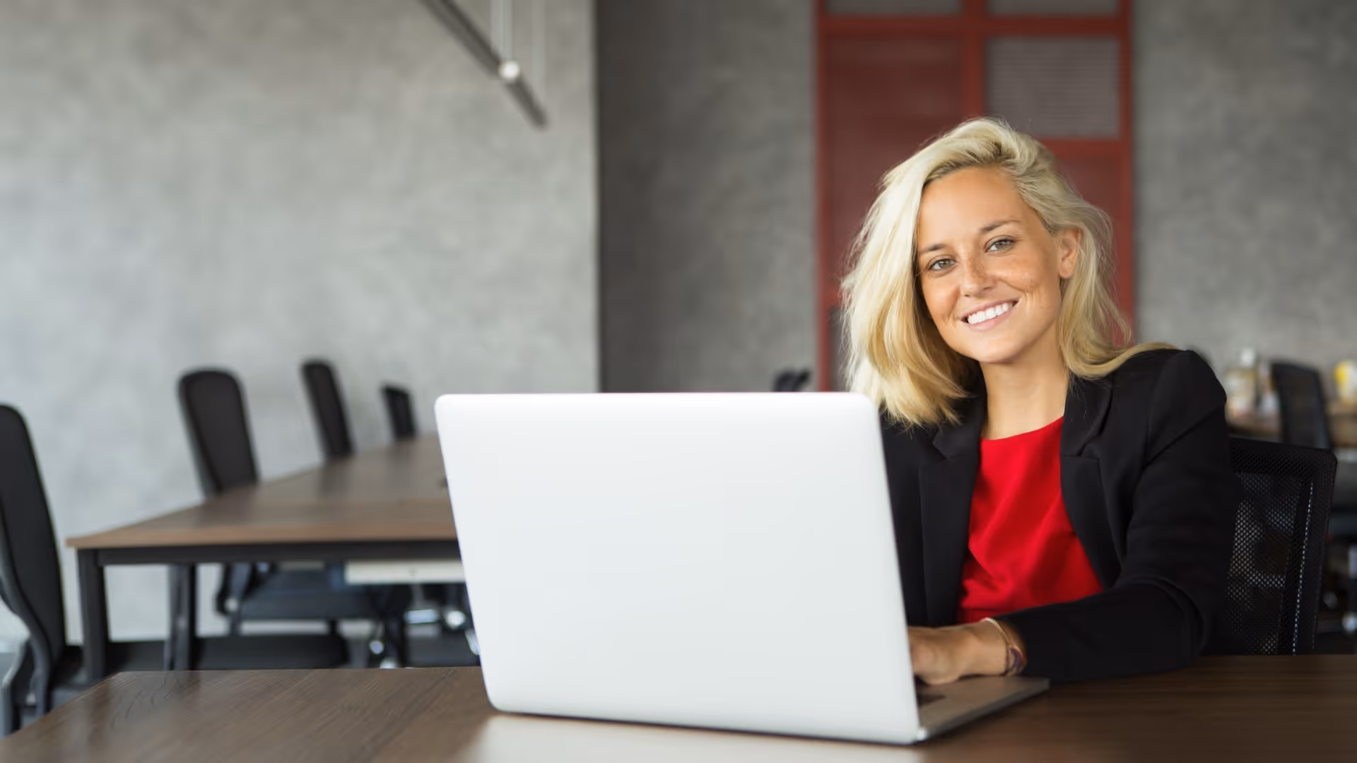 Woman smiling behind laptop, making digital work instructions