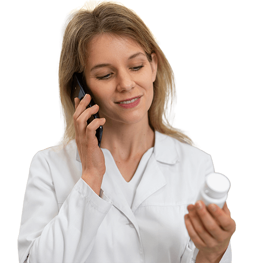 A pharmacist looks at a prescription bottle while on the phone. 