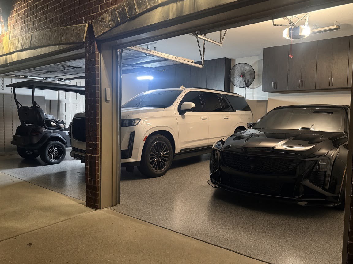 Dark wood-grain wall cabinets in a three-car garage with a grey flake epoxy floor