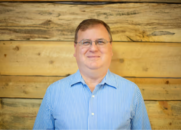 Photo of a man with eyeglasses wearing a striped blue longsleeve smiling at Tower Hill First Presbyterian Church