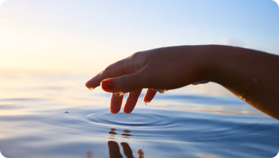 an image of a person's hand touch water causing ripples
