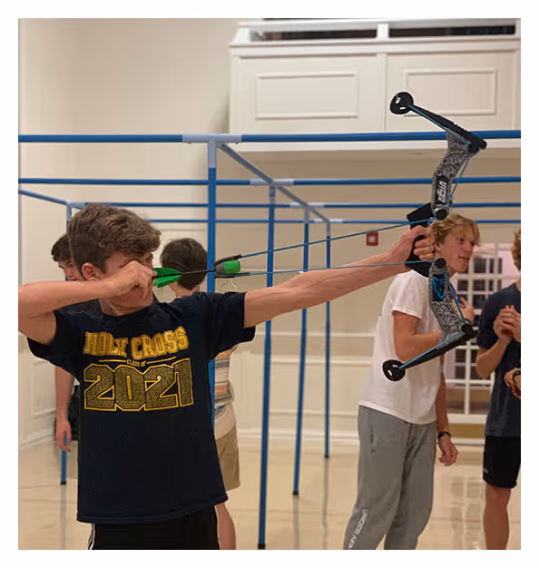 image of a boy holding a bow during an archery sports class at Towerhill church