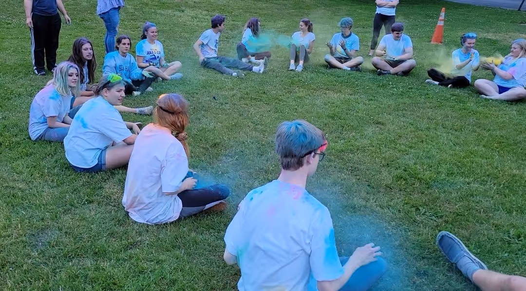 image of a group of young adults in a cricle playing with colors at towerhill church