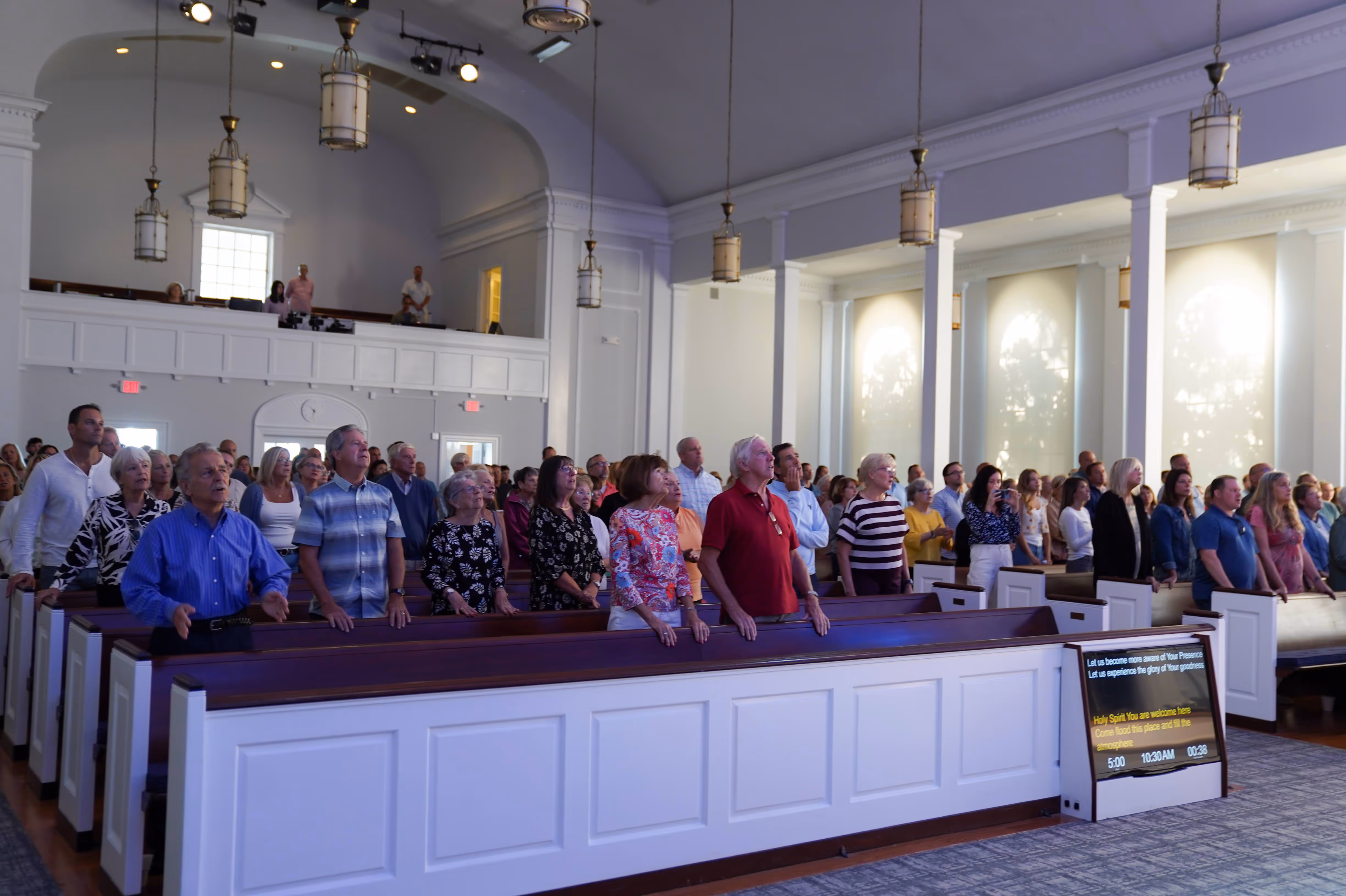 image of a group of people raising hands while listening to a live worship