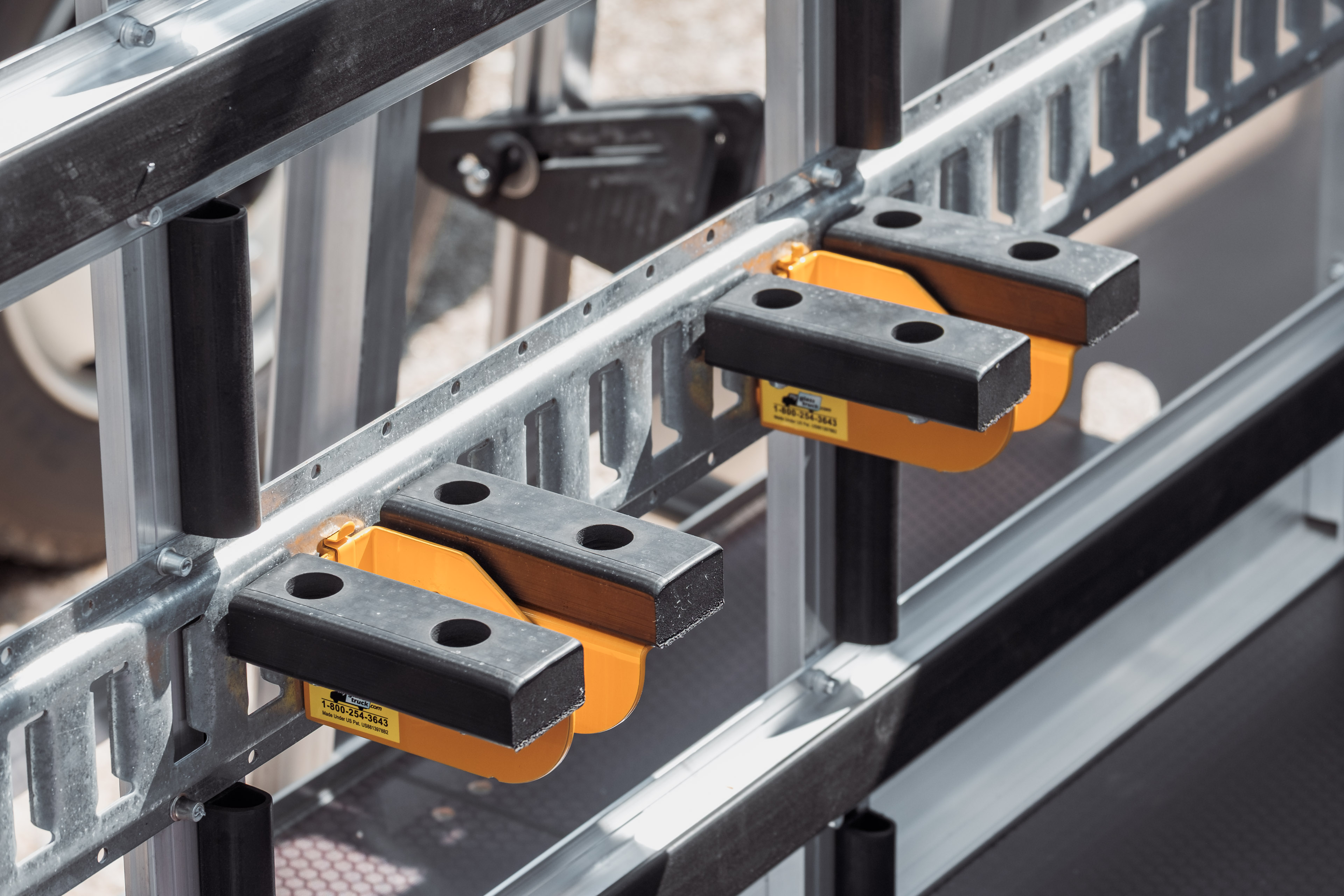 Close-up of Second Ledge brackets attached to E‑Track on a glass rack, creating an upper support tier.