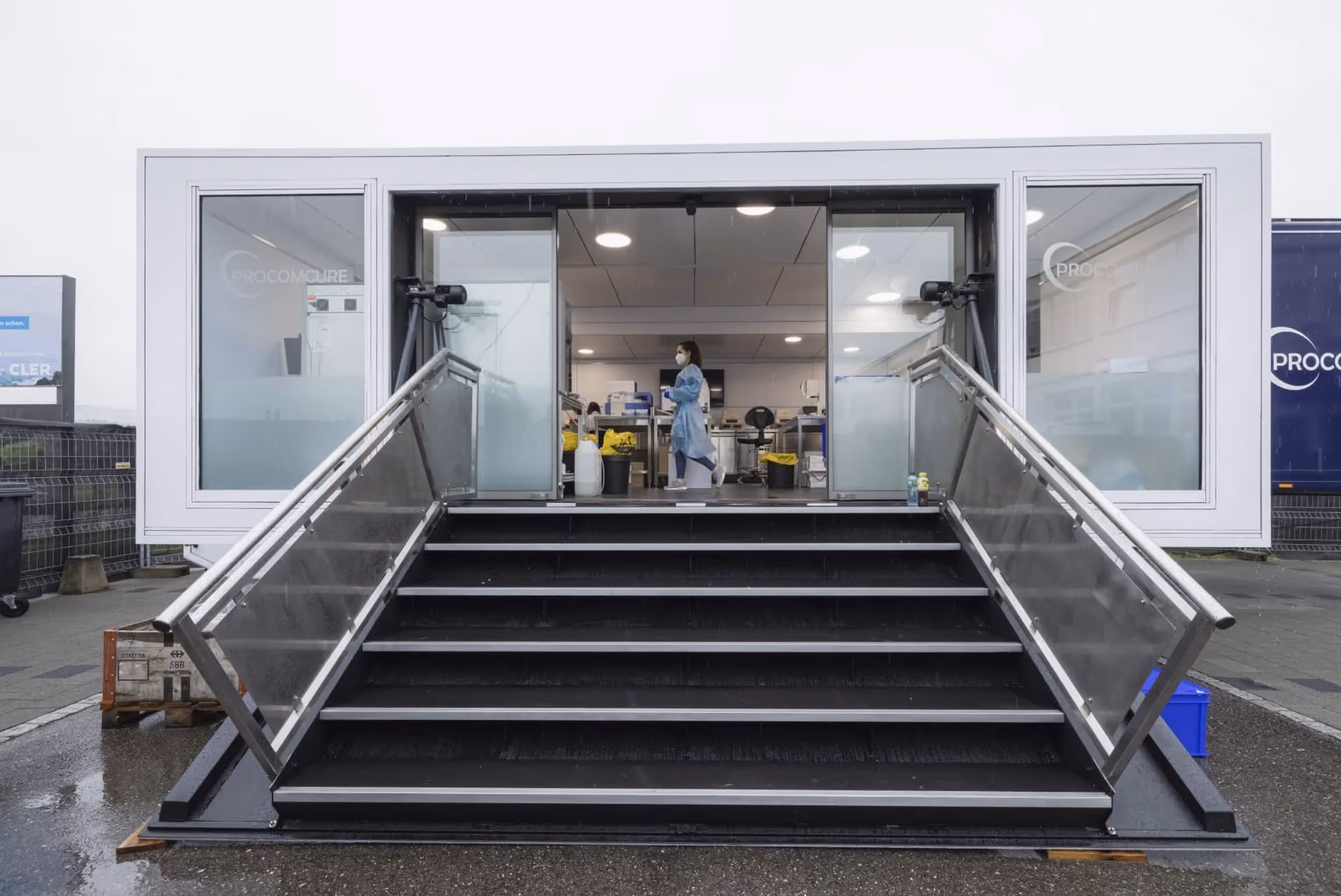 Laboratory container module with glass entrance and metal ramp stairs for mobile research.