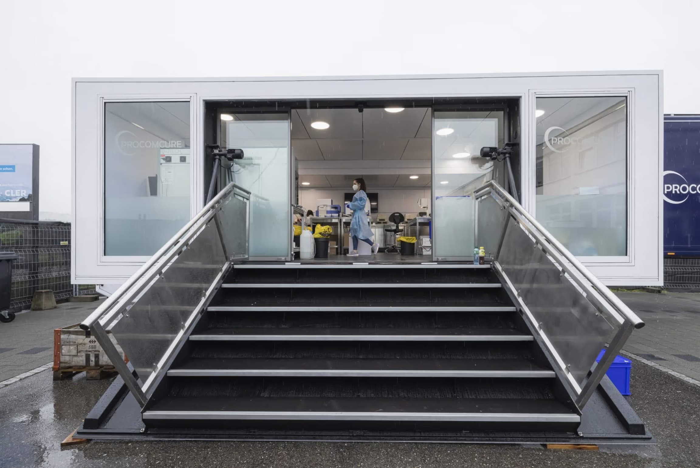 Mobile Laborcontainer mit ausfahrener Rampe, Arbeiter in moderner Inneneinrichtung sichtbar.