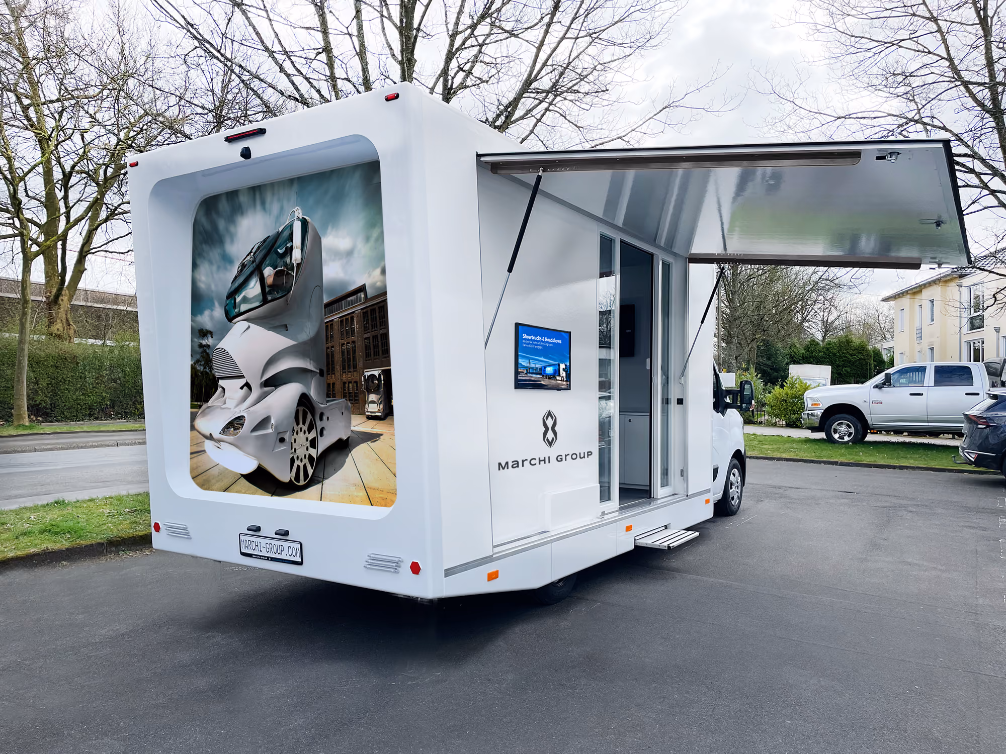 Weißer Marchi Drive Info Van mit Marchi Group Branding auf der Rückseite und ausgeklappter Seite.