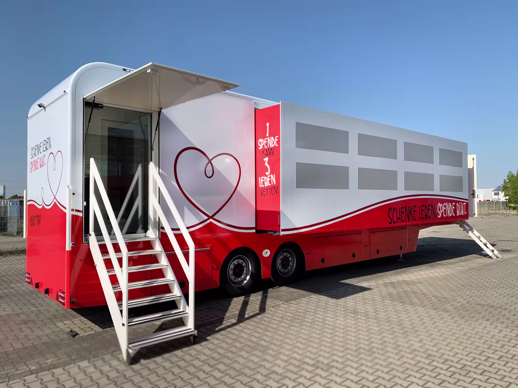 Front view of blood donation mini-truck with open door and red and white branding.