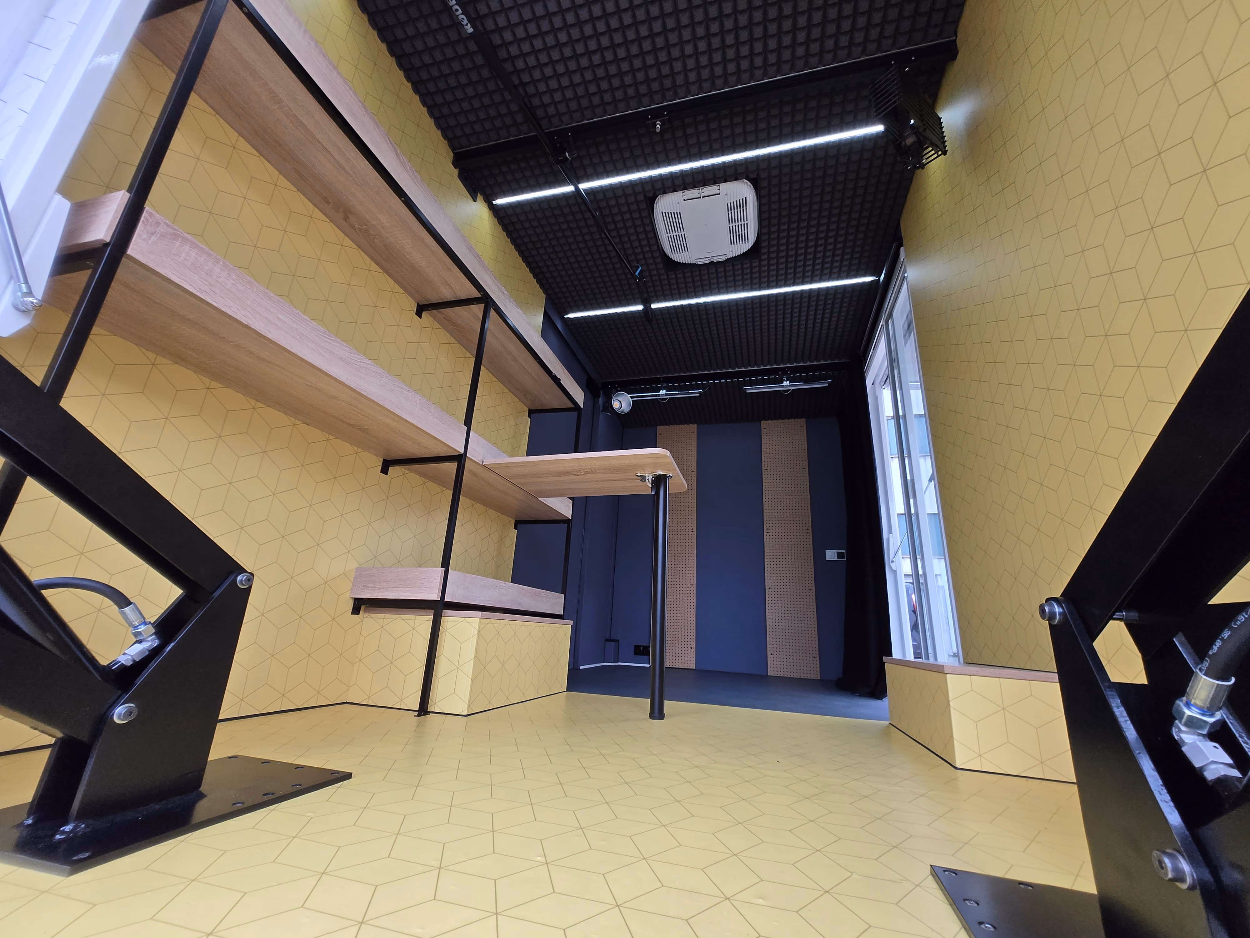Workshop space in a van, fitted with LED lights and wooden shelves.