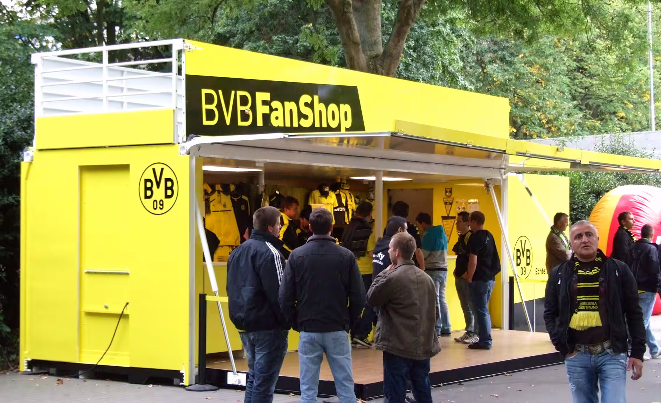 BVB FanShop Merchandise-Container in Gelb-Schwarz mit Besuchern und Fußball-Merchandise.
