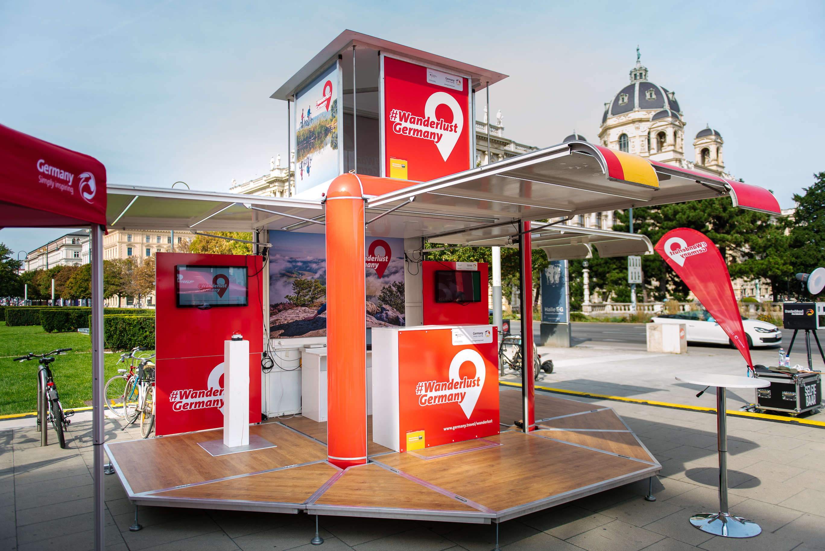 Aufgeklappter Promotion Cube Anhänger mit rotem Design für #WanderlustGermany Kampagne auf öffentlichem Platz.