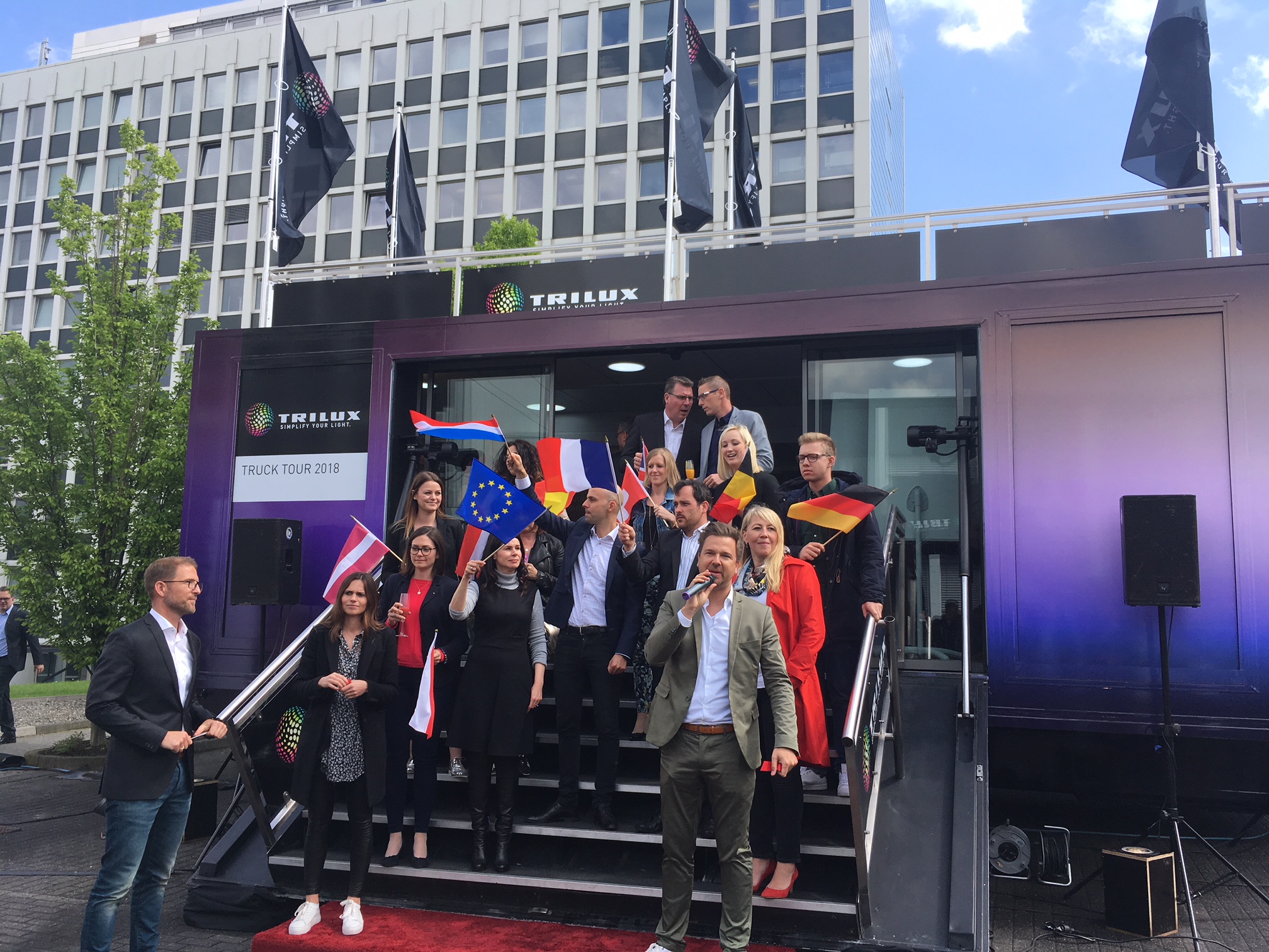 Gruppe von Menschen mit europäischen Flaggen vor einem TRILUX Truck Tour 2018 Fahrzeug