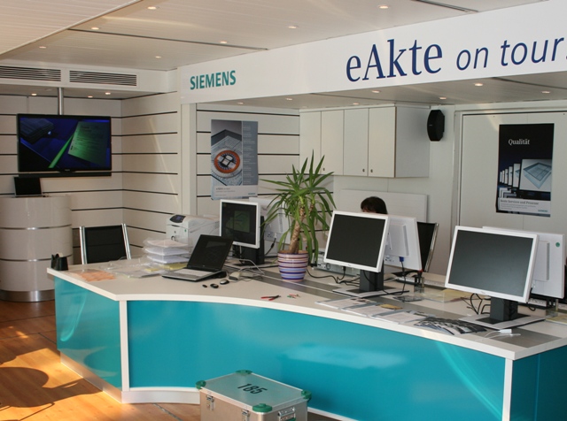 Moderne Siemens eAkte on tour Ausstellung mit Computern und Ausstellungswand.