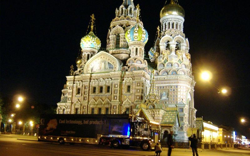 howtruck vor beleuchteter russischer Kirche mit goldenen Kuppeln nachts.
