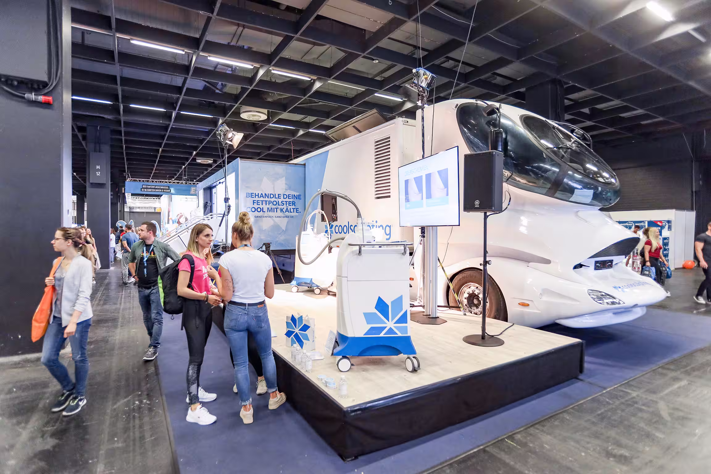 Blau-weißer Design-Truck als Messestand. Davor stehen Besucher und eine leicht erhöhte Plattform mit ausgestellten Coolsculpting Produkten.
