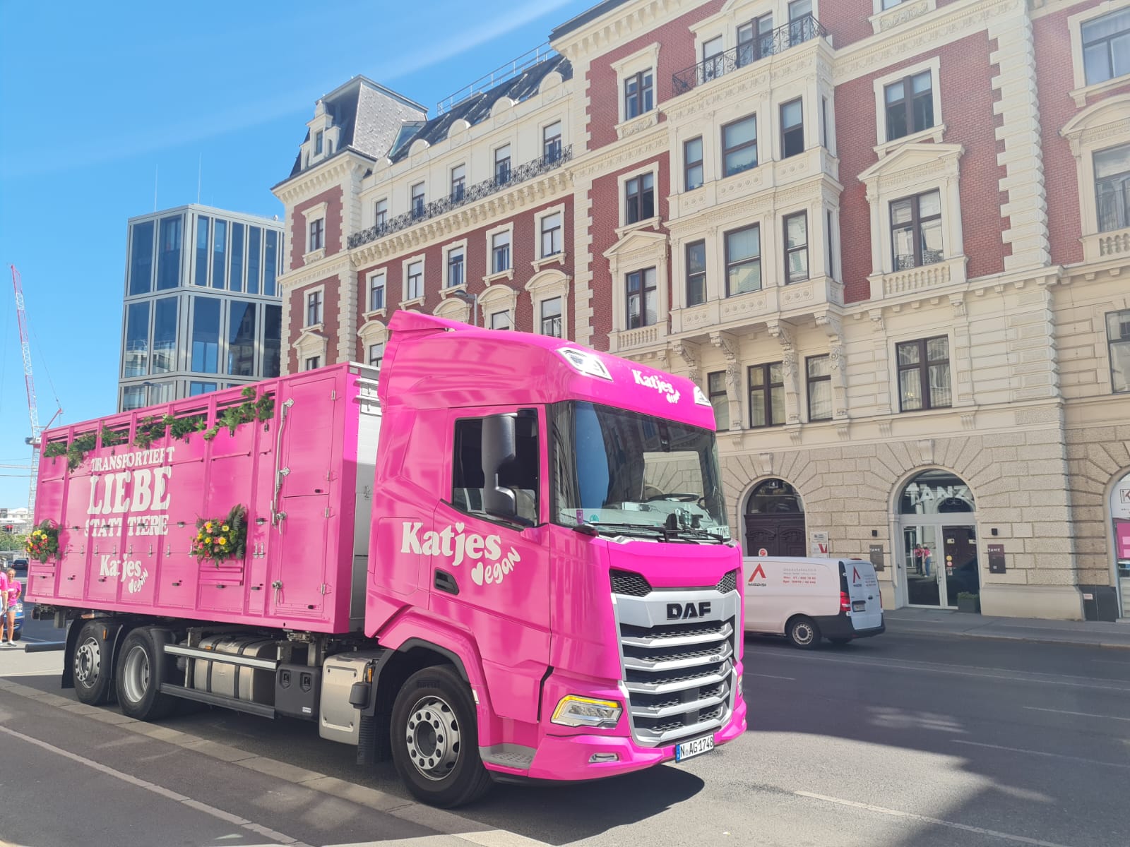 Show-LKW mit pinker Lackierung und Blumendekorationen vor historischen Gebäuden.