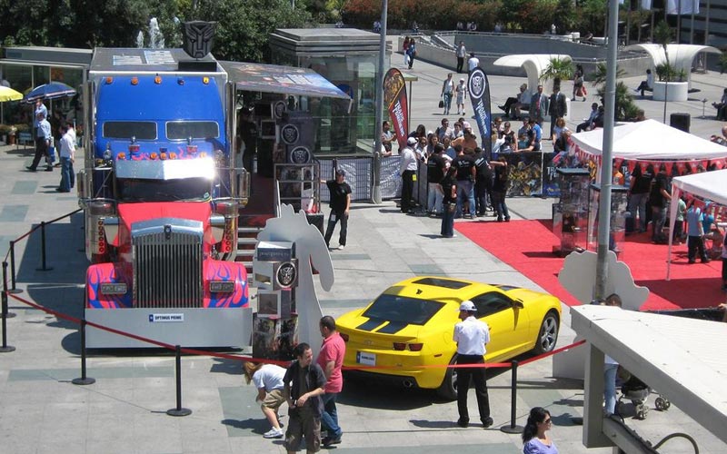 Event auf Stadtplatz: Großer Showtruck der aussieht wie Optimus Prime, ein knallgelbes Sportauto, roter Teppich und ein paar Zelte.