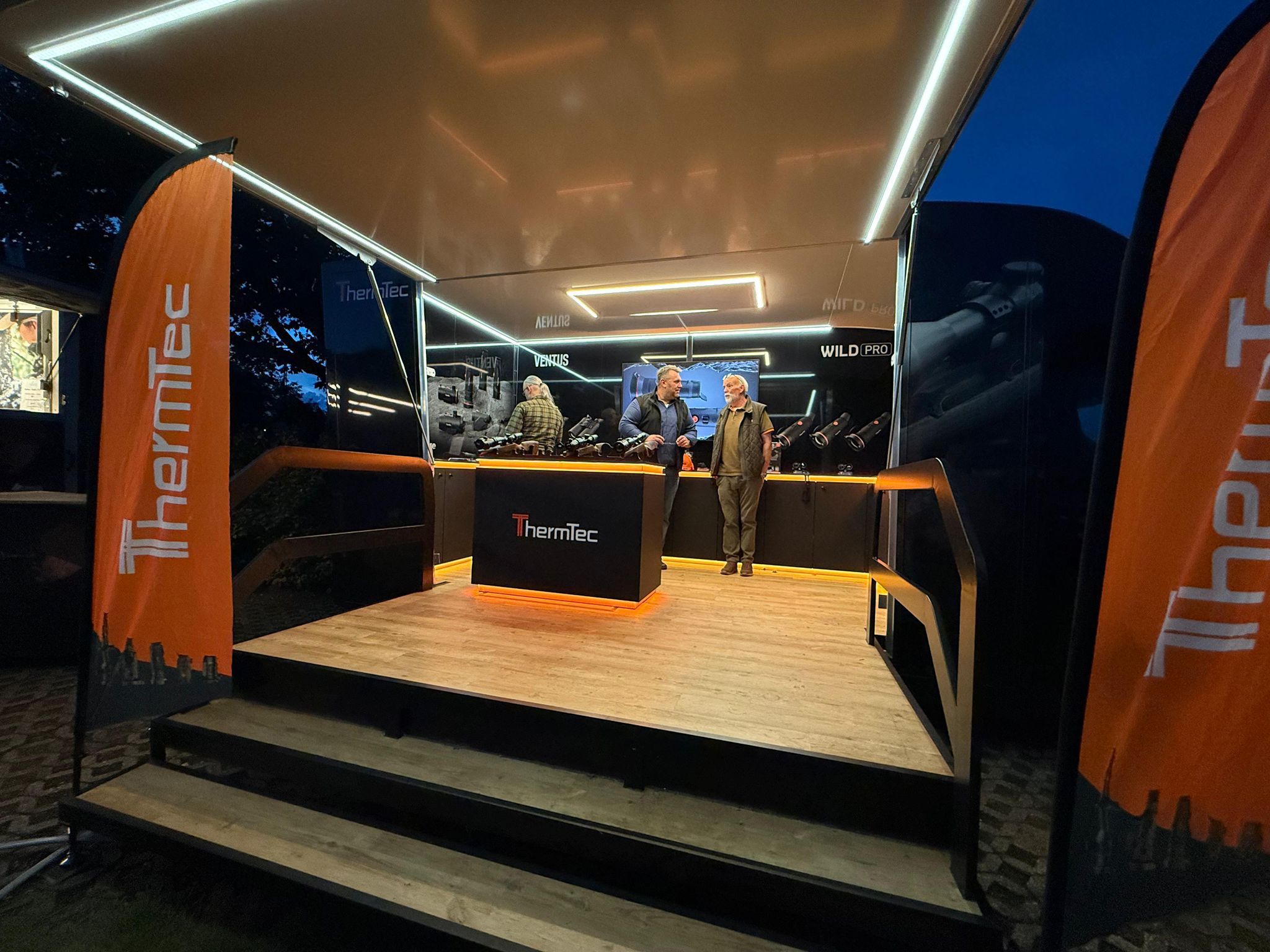 Blick ins Innere des Lippejagd Präsentationsfahrzeugs: Orangene LED-Beleuchtung, Wandtresen und freistehendes Modul mit ausgestellten Jagd-Produkten.