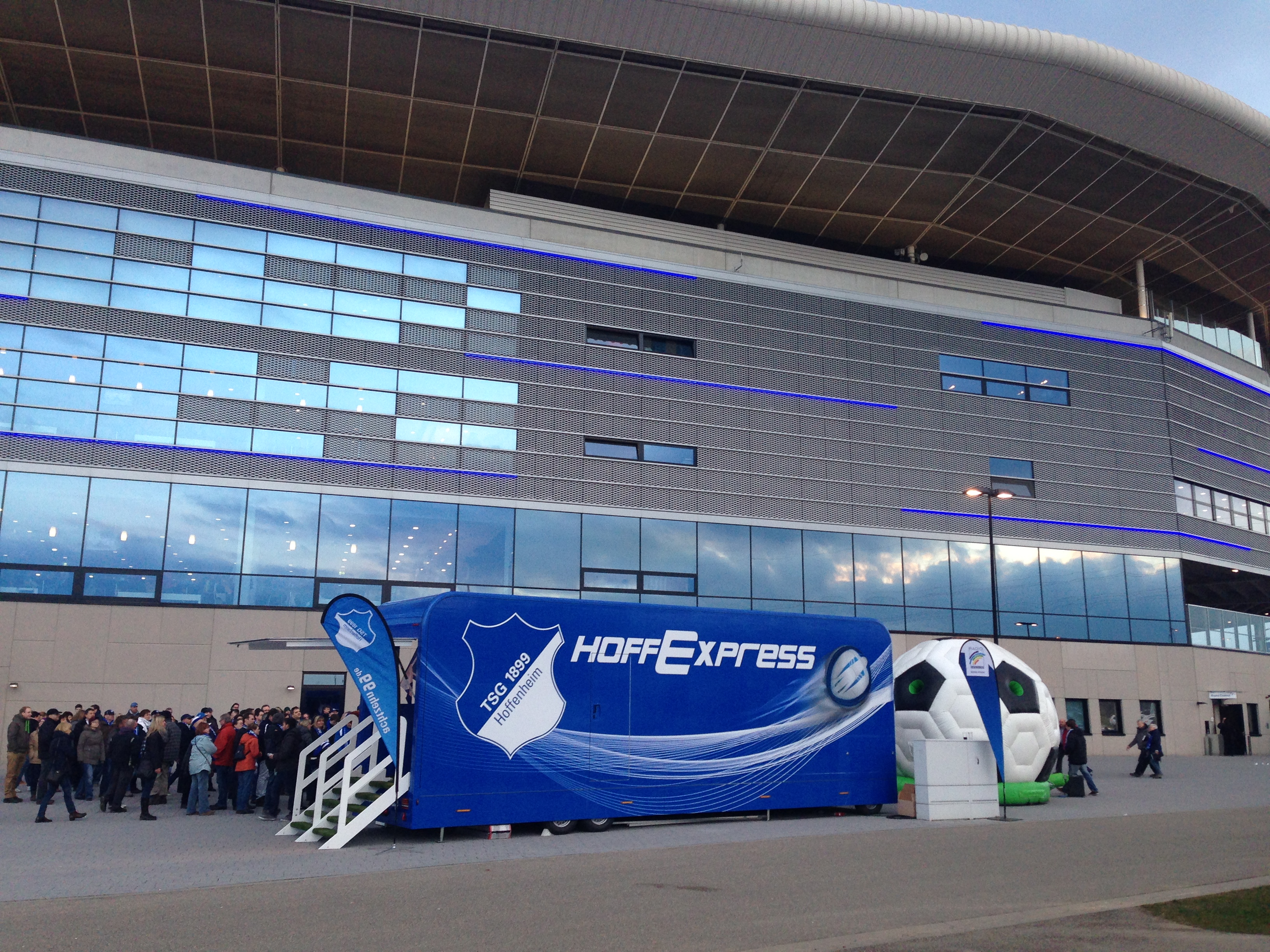 Hoffexpress Showtruck mit Fußball-Design vor modernem Stadion, Besuchergruppe.