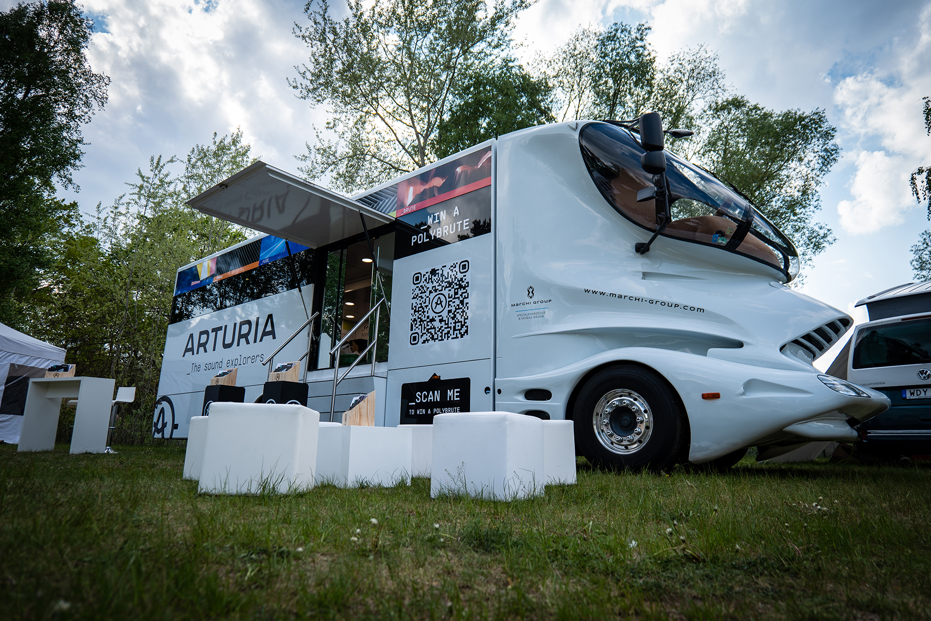 Weißer Showroom Design-Truck von Arturia: Futuristisches Cockpit, nach oben geöffnete Türklappe mit Treppe, die ins Innere führt. 
