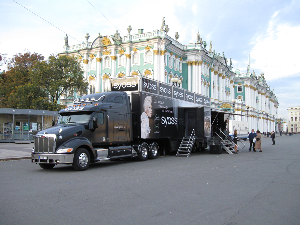 Schwarzer Showtruck mit Syoss-Branding vor prächtigem Schlossgebäude mit Besuchern.