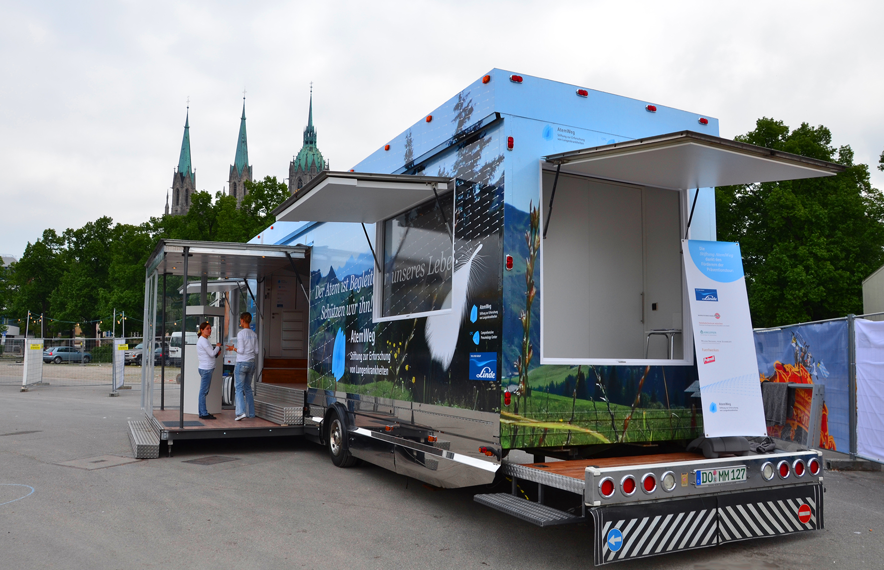 Großer blauer Info-Truck mit ausgefahrenen Bühnen und aufgeklappten Fenstern.