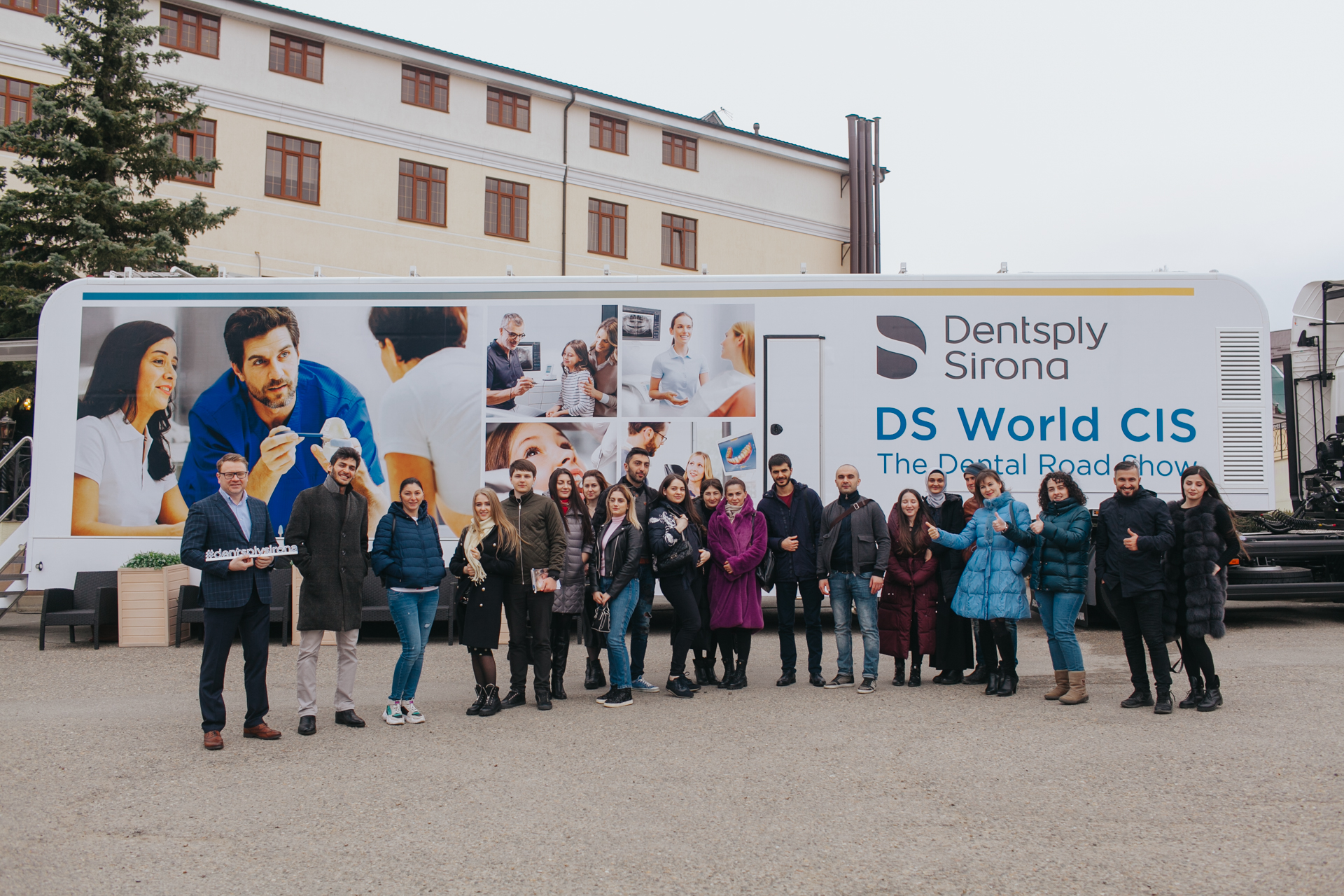 Gruppe von Menschen posiert vor einem weißen Showtruck der Dentsply Sirona DS World CIS.