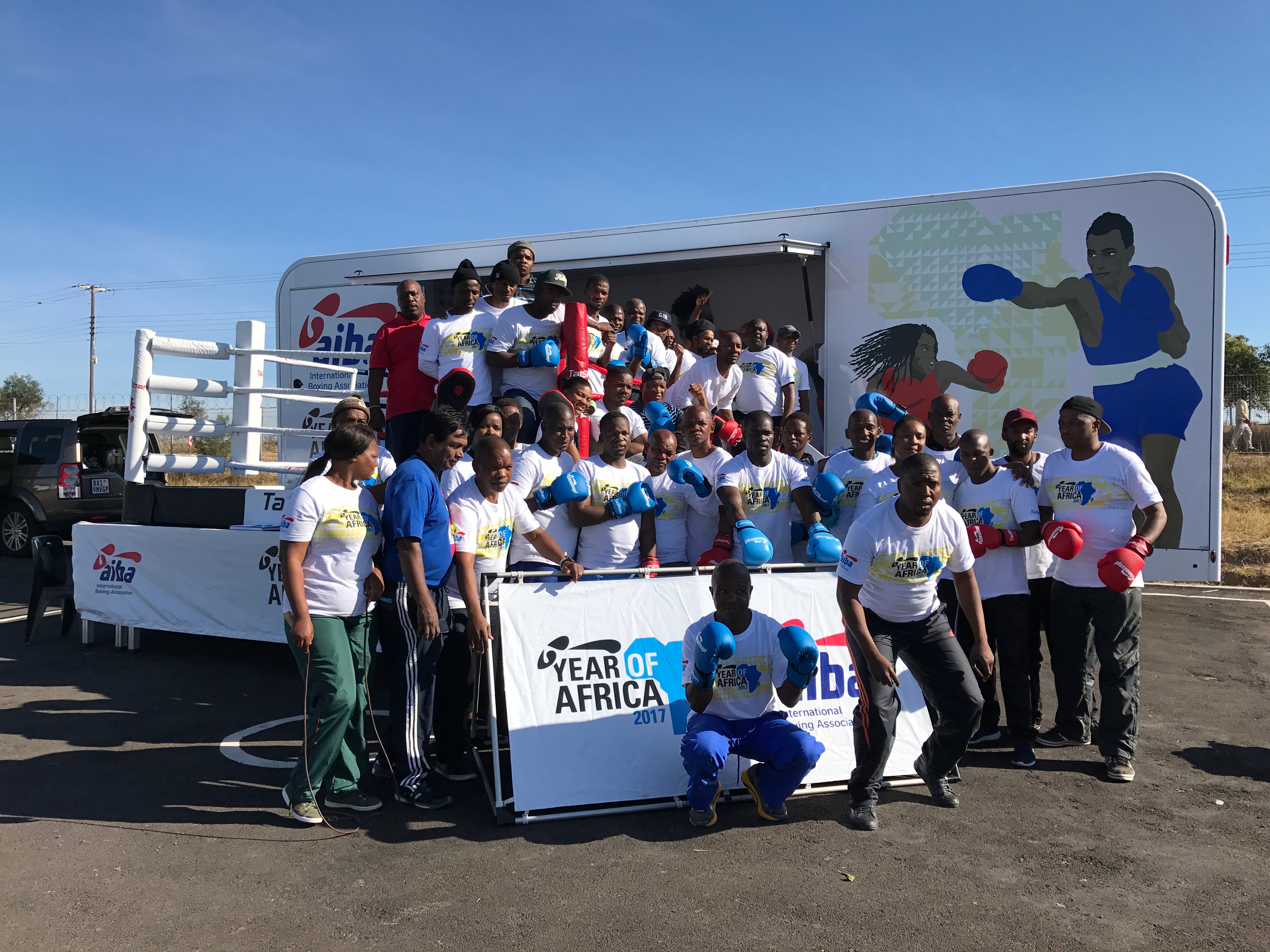 Große Gruppe von Boxern und Trainern mit Handschuhen vor einem mobilen Boxring mit "Year of Africa 2017" Banner.