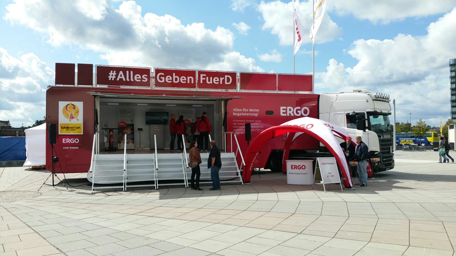 Promotion Truck mit weißer Kabine und rotem Sattelauflieger: Große Seitöffnung mit Treppe bietet Blick auf Beratungsraum im Inneren. 