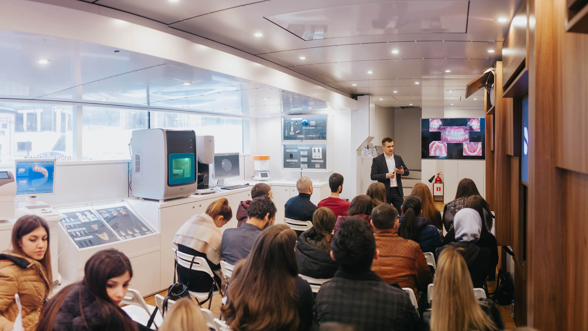 Speaker presenting to dental professionals inside the Marchi Classic event semi-trailer for Dentsply Sirona.