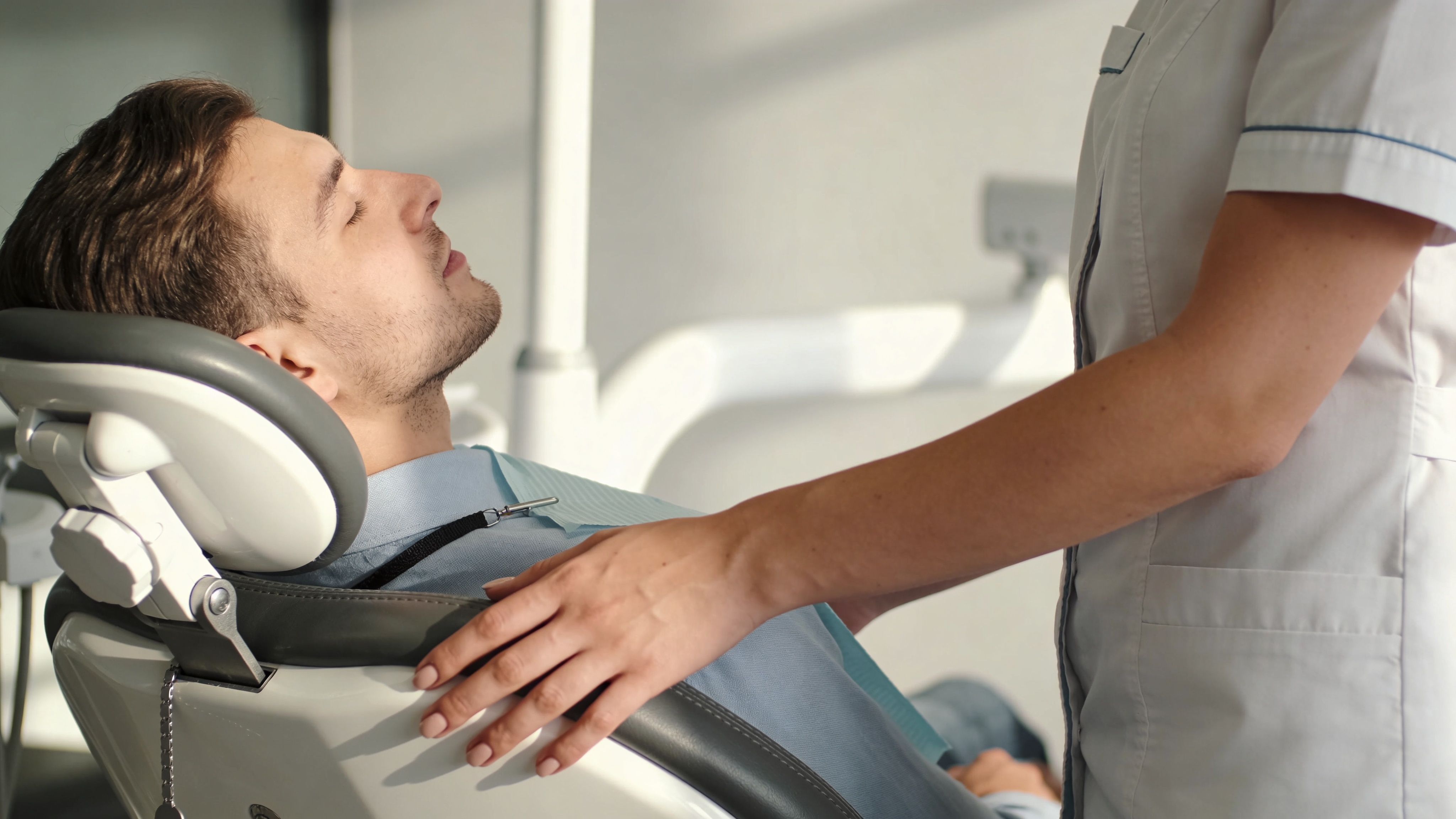 A professional dentist providing comfort to a male patient resting in a dental chair during a visit.