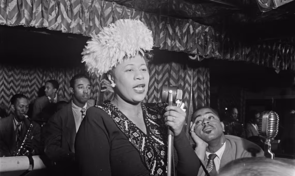 Ella performs with the Dizzy Gillespie Big Band in 1947 as Dizzy looks up in awe.