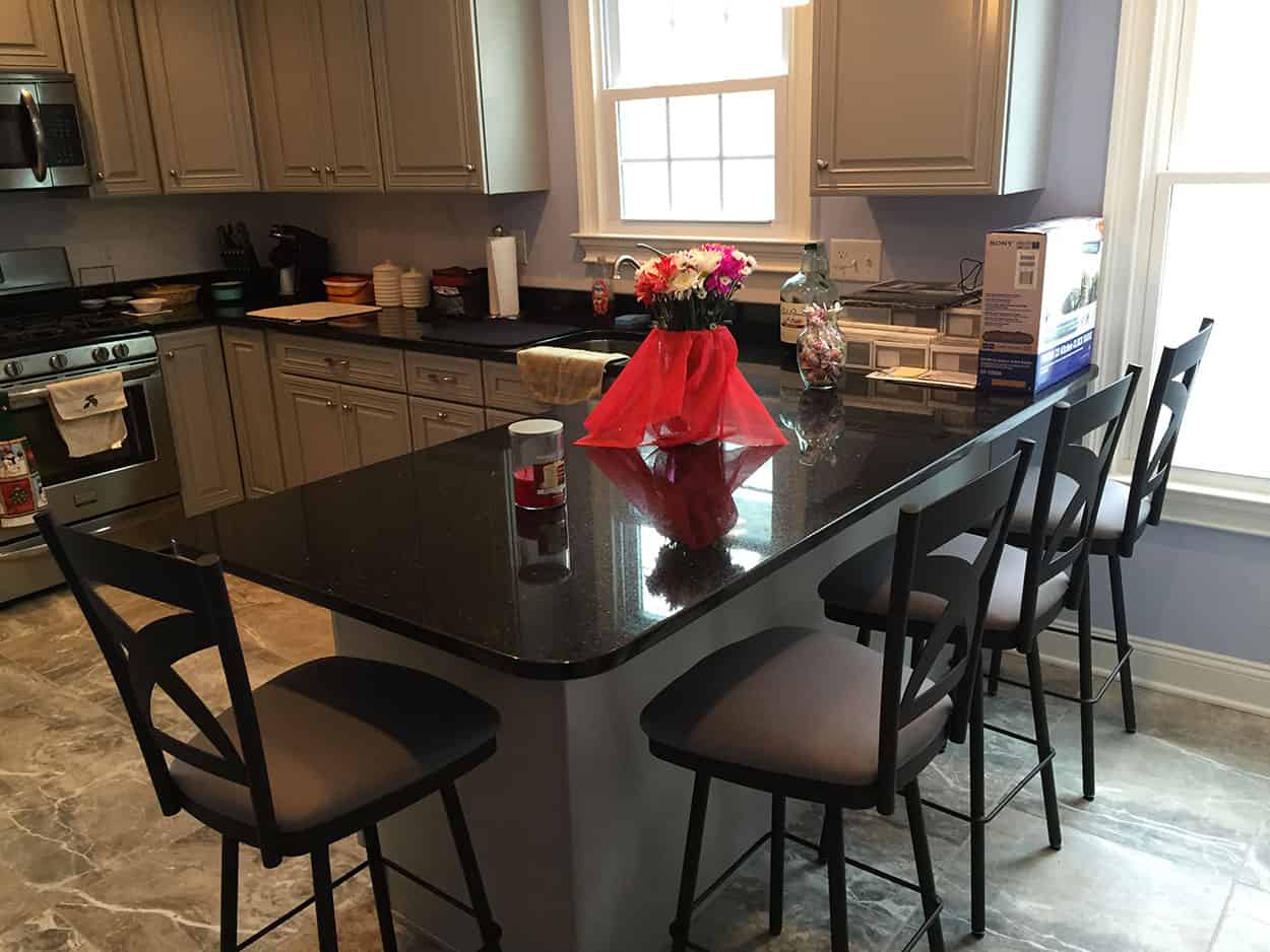 four black kitchen stools at a black marble counter