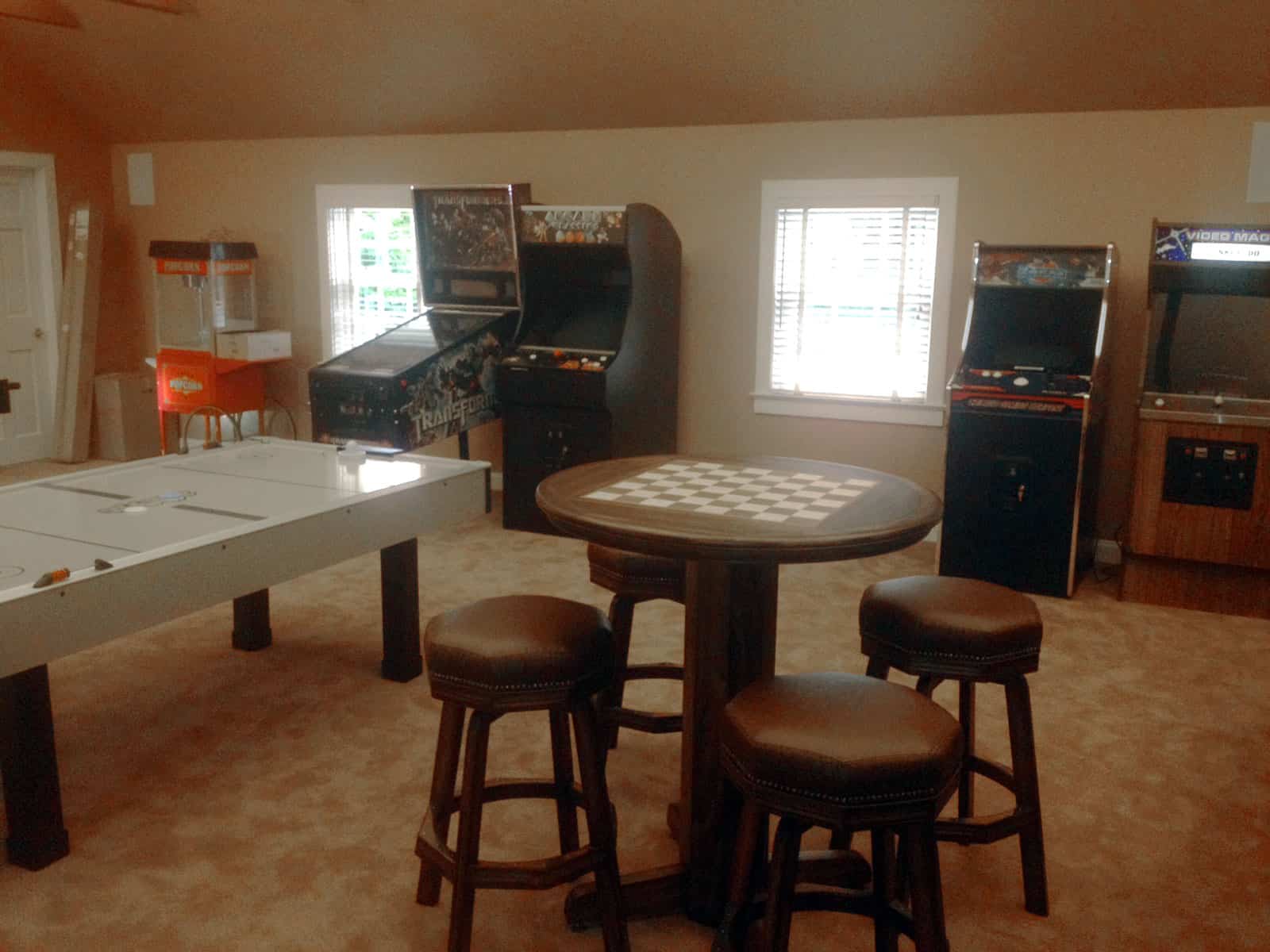 air hockey, popcorn machine, pinball, three arcade games, chess table in a game room