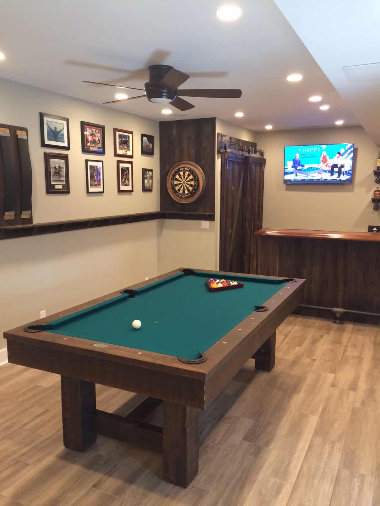 green pool table with darts and a tv