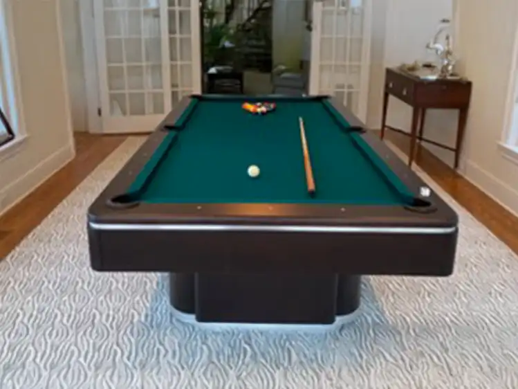Modern Olhausen Plaza pool table with teal felt, pedestal base, enclosed rails, and brushed aluminum trim in a bright home game room setting.