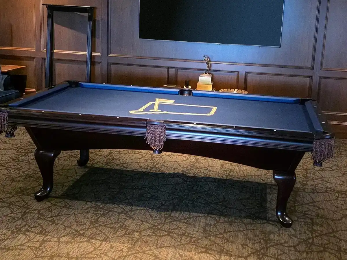 Elegant dark wood refelted pool table with navy blue felt featuring a gold Masters golf log with fringed pockets and cabriole legs.