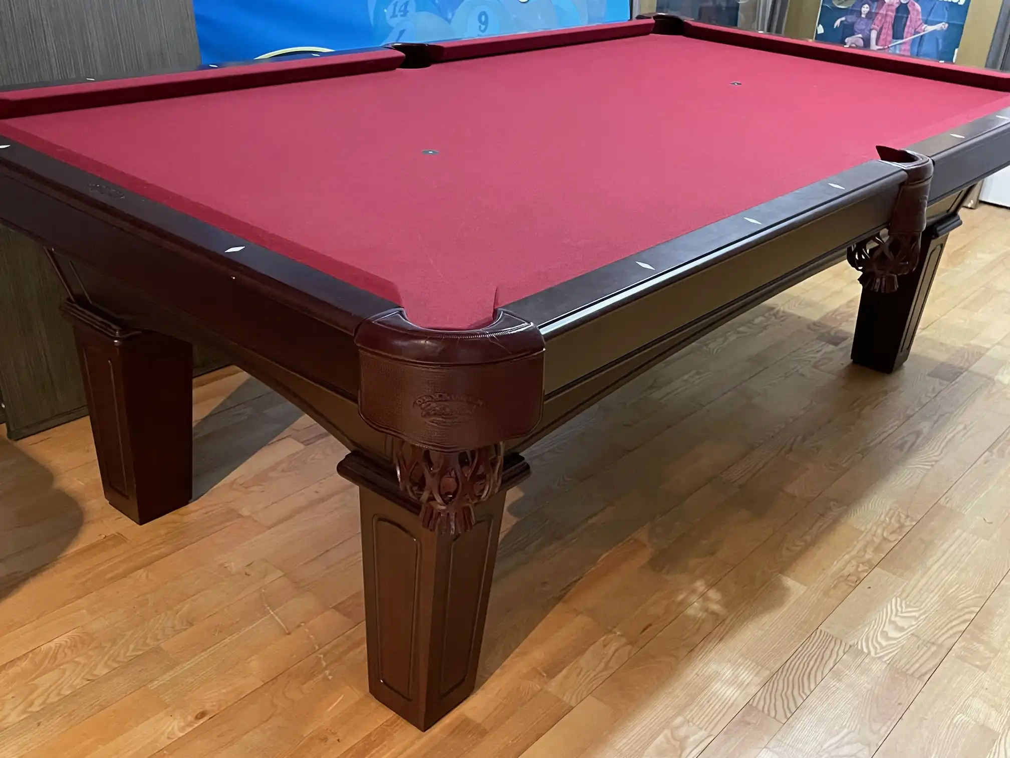 Olhausen Belmont pool table featuring a cherry finish, red burgundy felt, diamond sights, and decorative carved legs