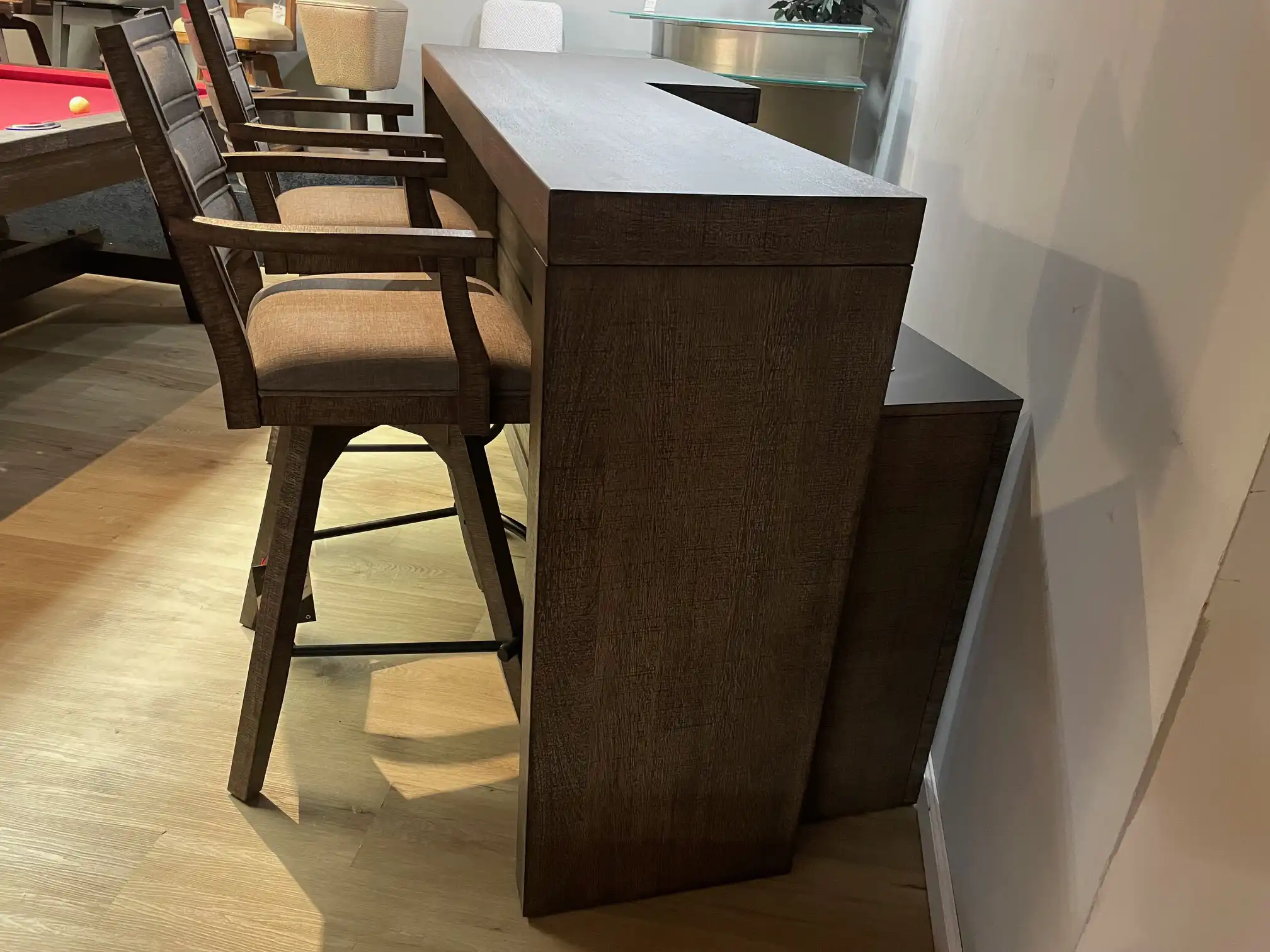 Side view of the ECI Furniture Spring Haven 4-piece bar set. It shows the 78x28x42 inch rustic wood counter and two matching swivel stools in a gameroom.