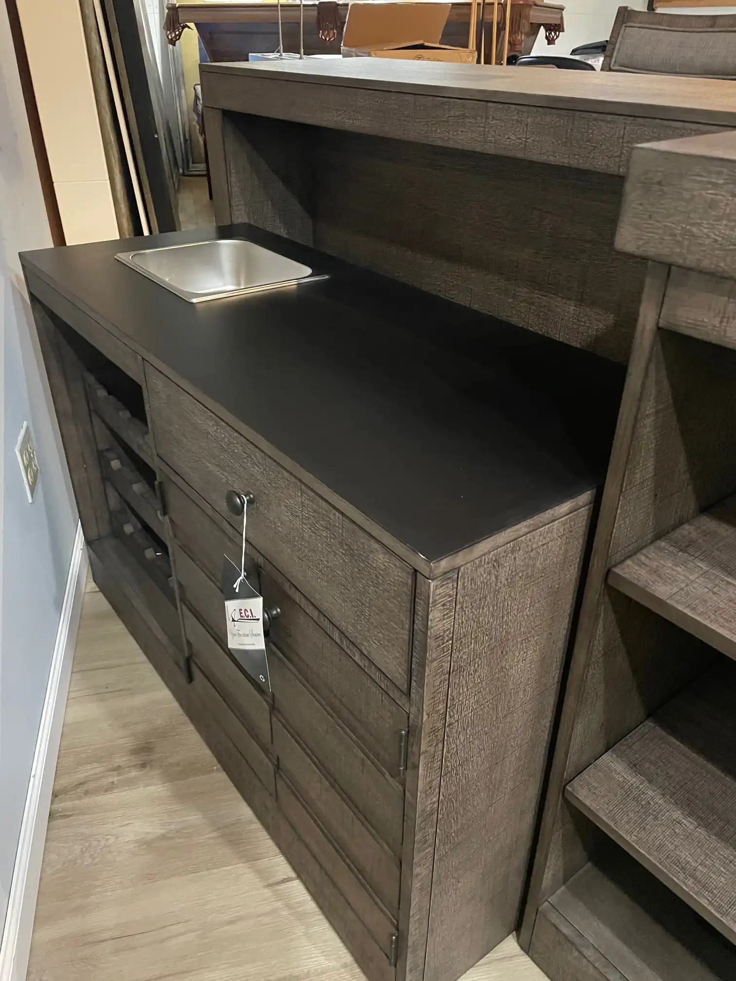 Close-up of the ECI Spring Haven gameroom bar working side. It highlights the built-in wine rack, storage drawers, dark counter, and small stainless sink.