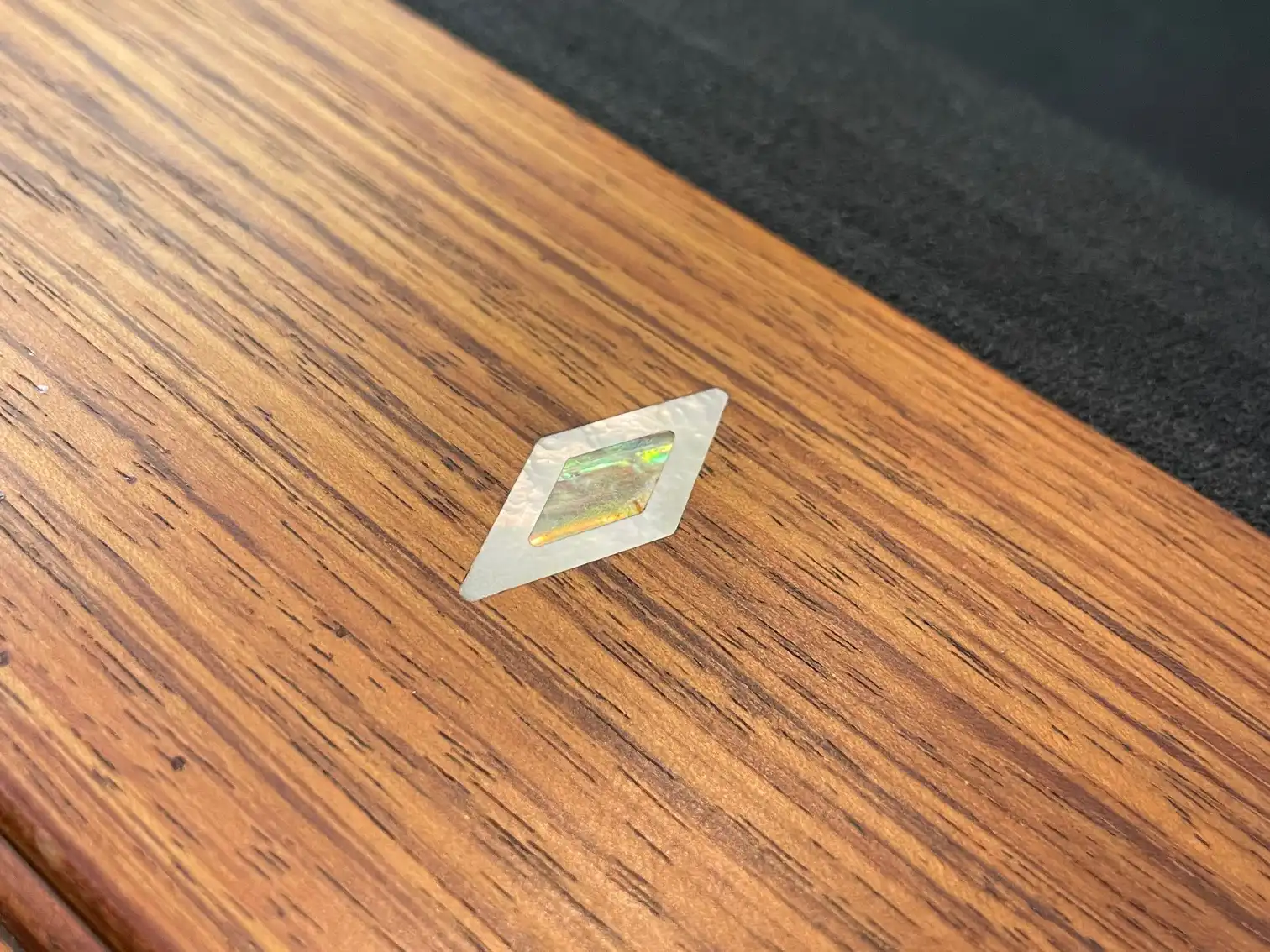 Close-up of an Olhausen Innsbruck pool table wooden rail showcasing an iridescent mother of pearl diamond-shaped sight inlay.