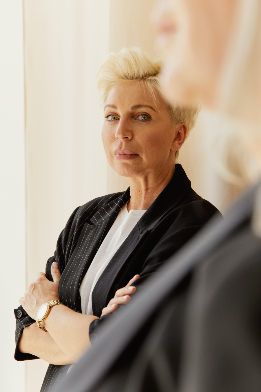 Confident, mature blonde woman in black blazer looking at camera