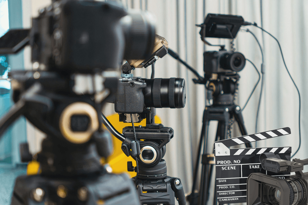 Multiple professional video cameras on tripods alongside a film clapperboard on a production set.
